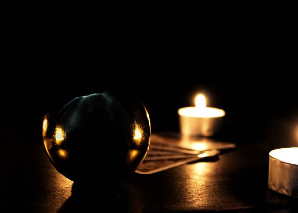 Tarot cards, magic ball and candles on a black background