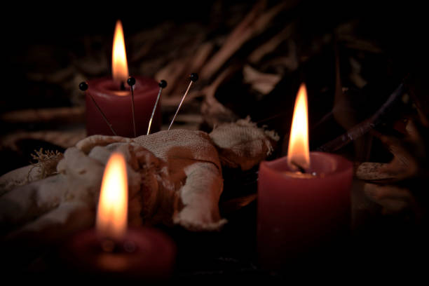 Occultist dripping hot wax on voodoo doll, magic rituals, black spell, horror