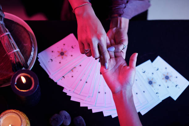 Fortune teller pointing at love line on palm of female client